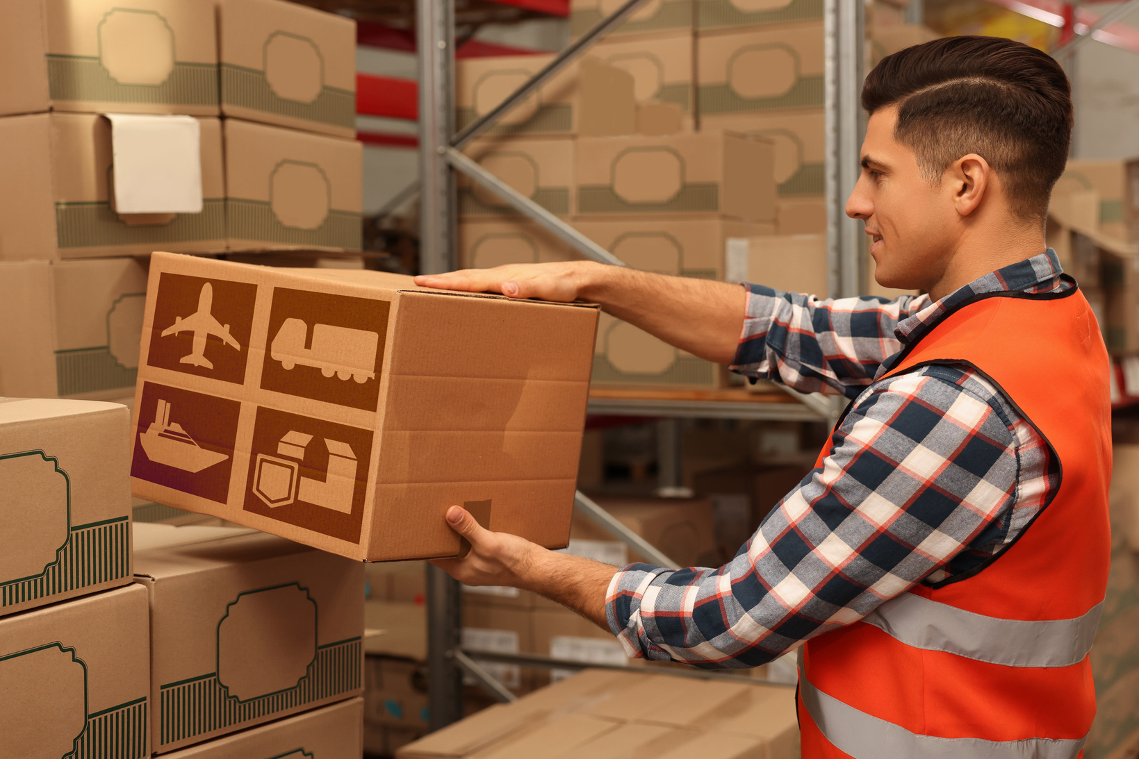 Worker Stacking Cardboard Boxes in Warehouse. Wholesaling